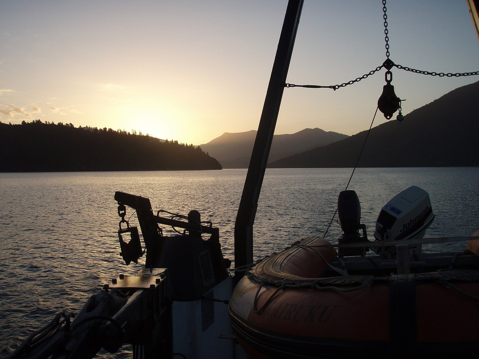Sunset over the water seen past the bow of a small boat