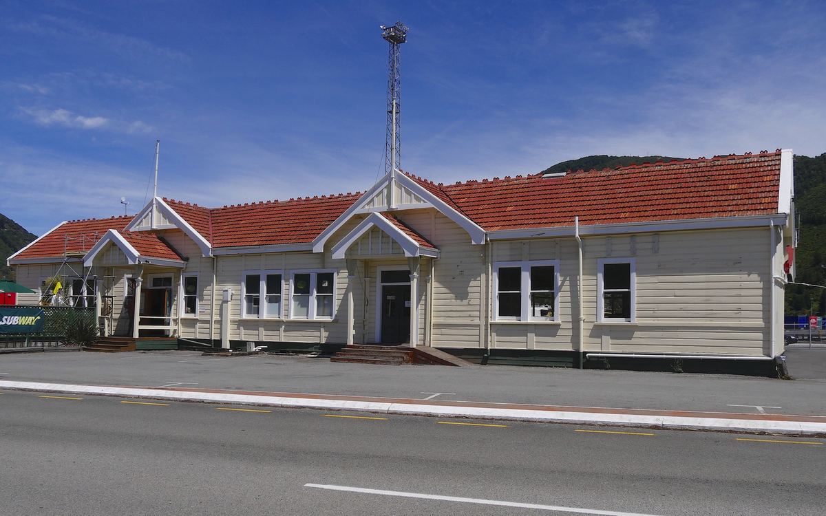 Cream and red-roofed railway station building beside a road