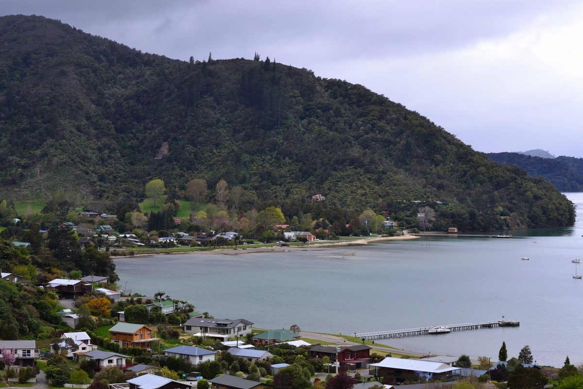 Elevated view across Anakiwa settlement, shoreline, jetties and the head of Queen Charlotte Sound/Tōtaranui.