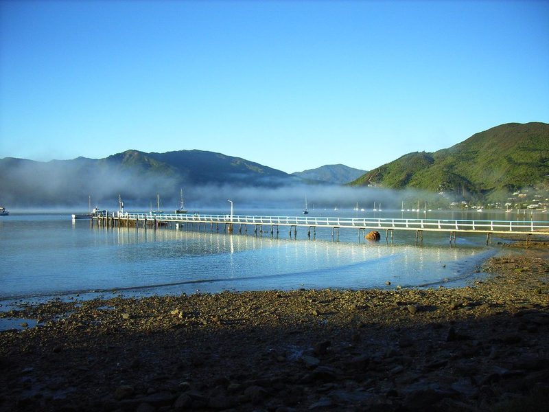 Anakiwa's long white waterfront jetty and sheltered bay in low morning mist.