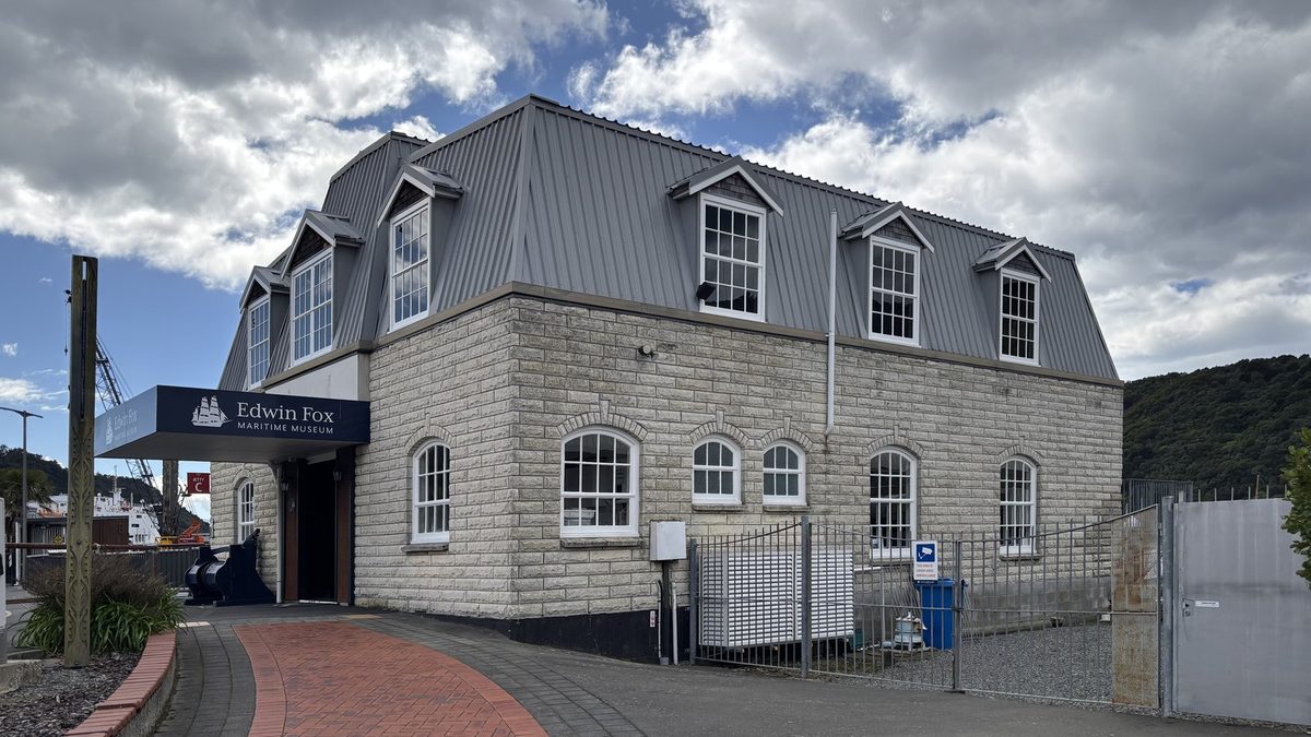 Signed main entrance and waterfront museum building under a partly cloudy sky.