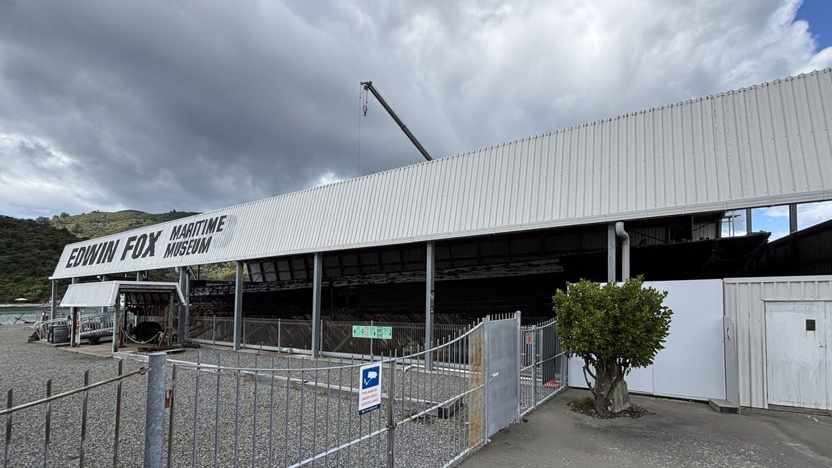 Edwin Fox hull visible inside its open-sided dry-dock shelter beside the waterfront.