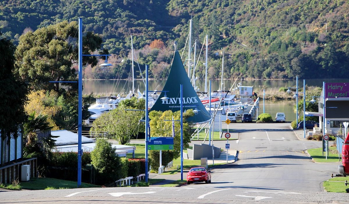 View down Havelock's main street toward the marina, with the Havelock gateway sign and Pelorus Sound beyond.