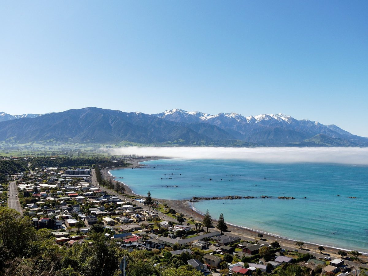 Kaikōura township and coast beneath the snow-dusted Seaward Kaikōura Range, viewed from the peninsula.