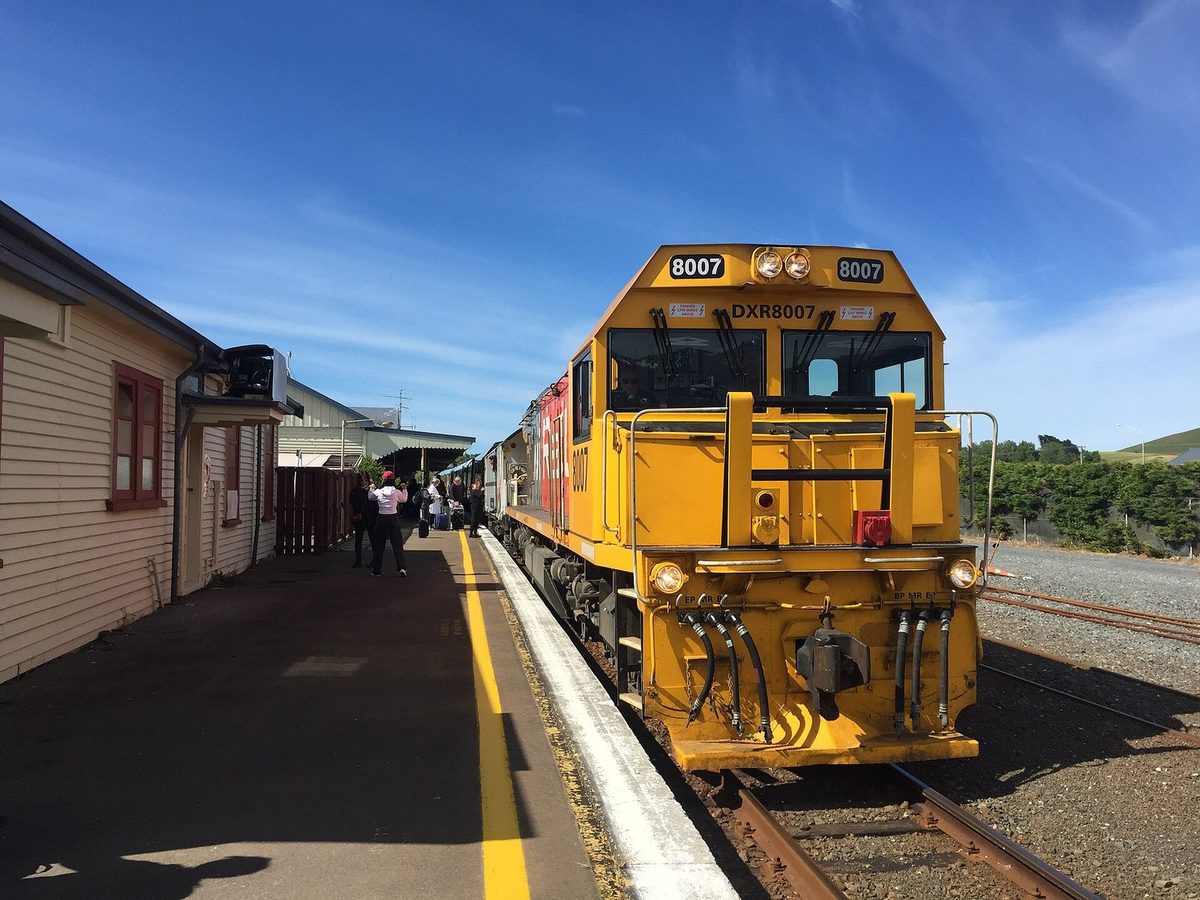 A Coastal Pacific locomotive and passenger train stopped at Kaikōura railway station.