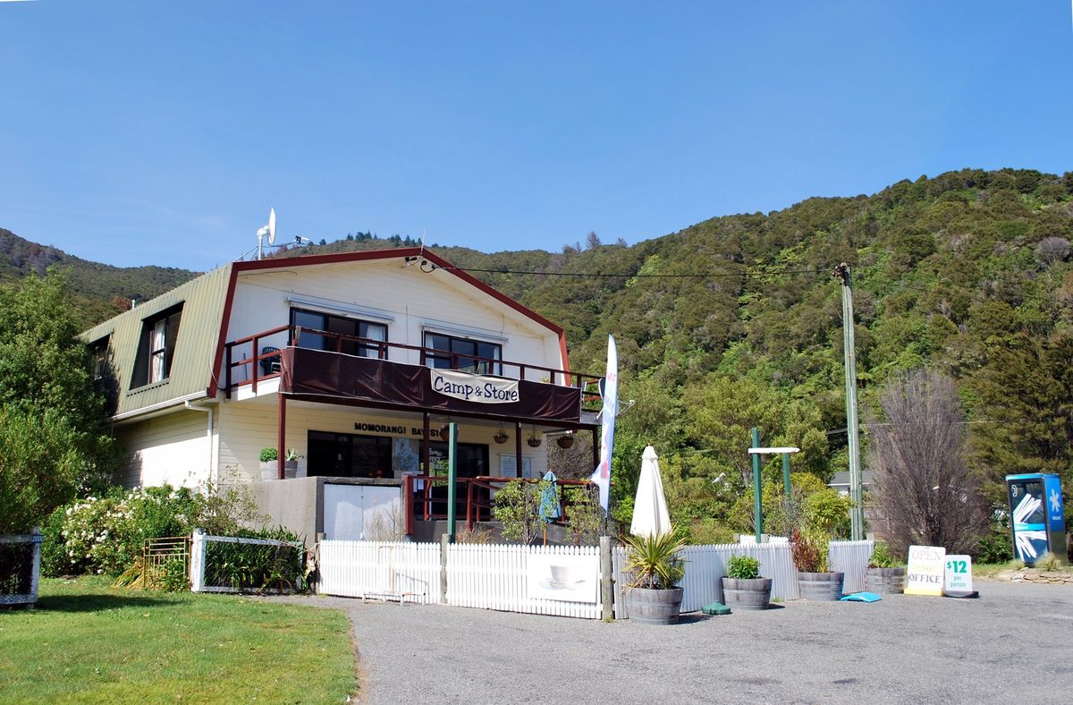 The Momorangi Bay Camp and Store building against the forested hillside.