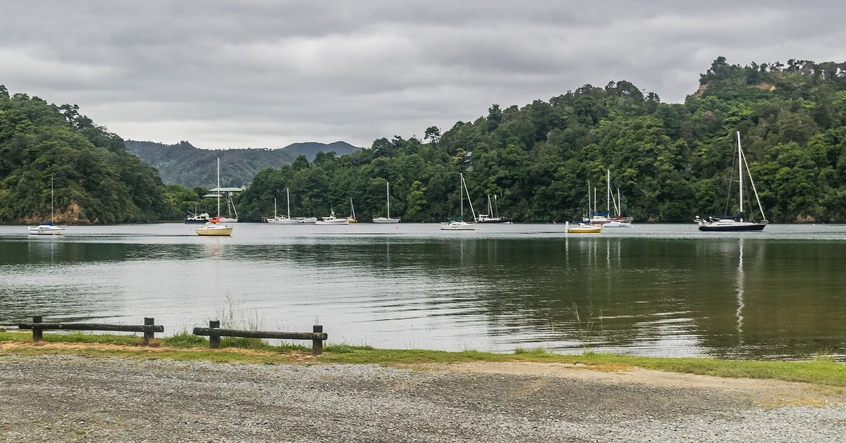 Calm water and yachts viewed from the gravel foreshore at Ngakuta Bay Recreation Reserve.