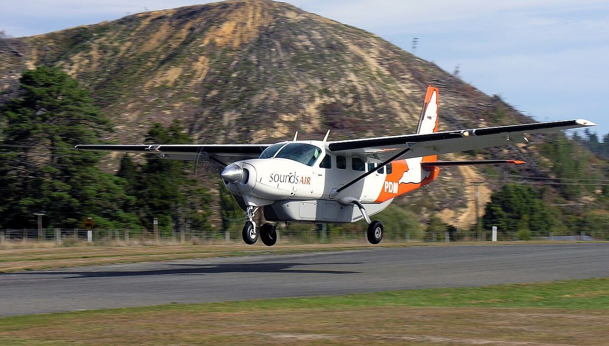 A Sounds Air Cessna 208 Caravan landing at Picton-Koromiko airfield, with wooded hills behind.