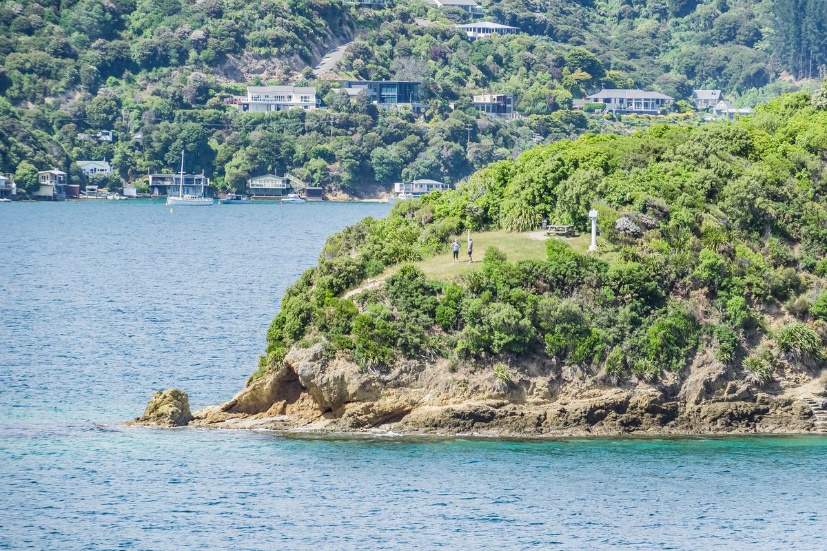 The Snout's shoreline lookout clearing, picnic table and two walkers, seen across the water from the south.