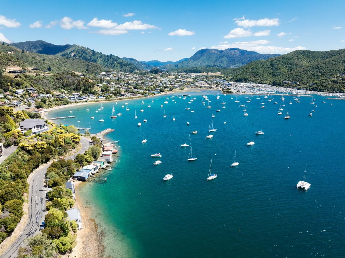 Aerial view across Waikawa Bay, its foreshore, moored yachts, settlement and Waikawa Marina.