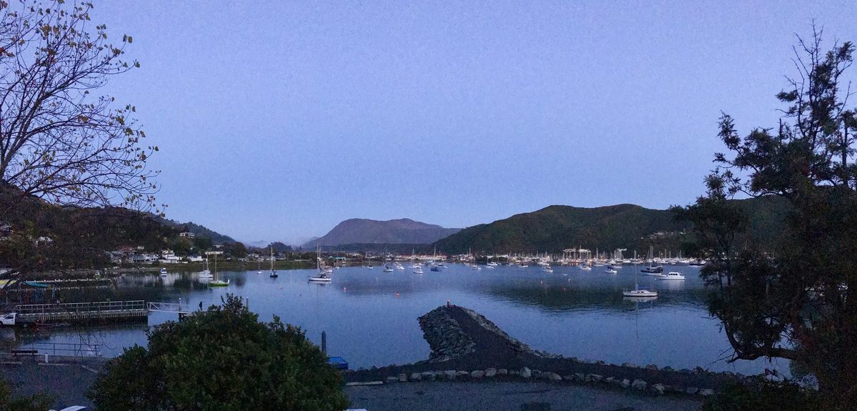 Waikawa Bay at dusk from the foreshore, with anchored boats and Waikawa Marina across the water.