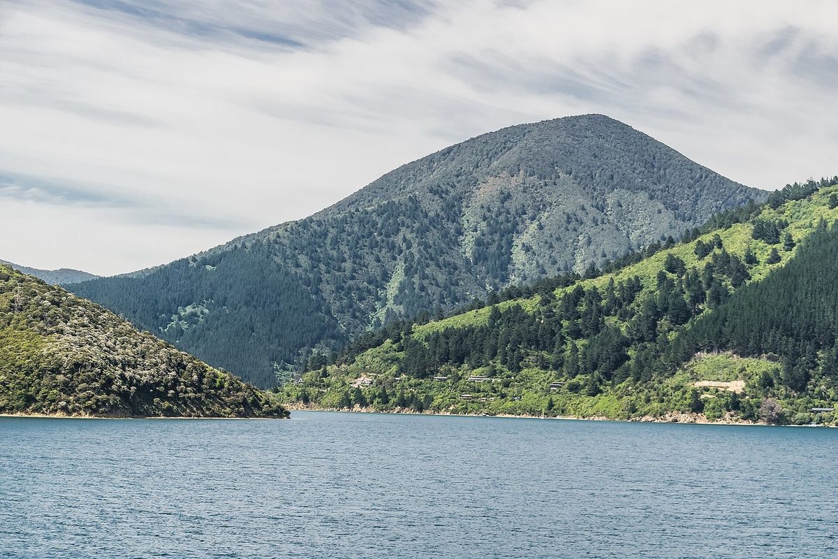 Closer view across Whatamango Bay to the wooded slopes, shoreline and prominent hill behind the bay.