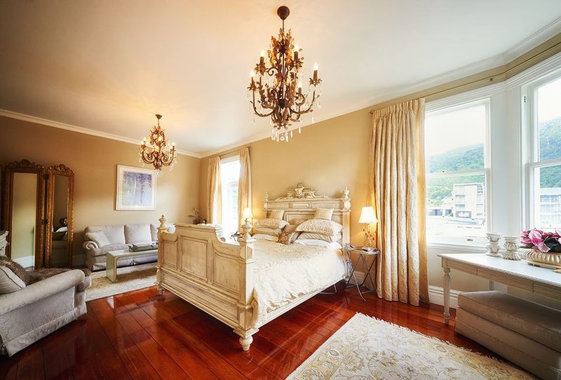 Formal Suite with carved king bed, chandeliers, polished timber floor and lounge seating.