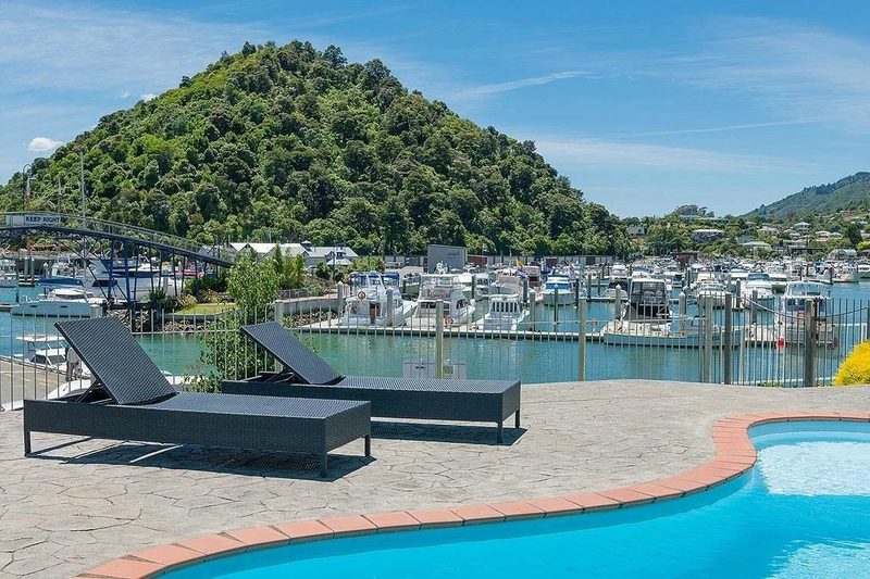 Hotel swimming pool and loungers overlooking Picton marina and its moored boats.