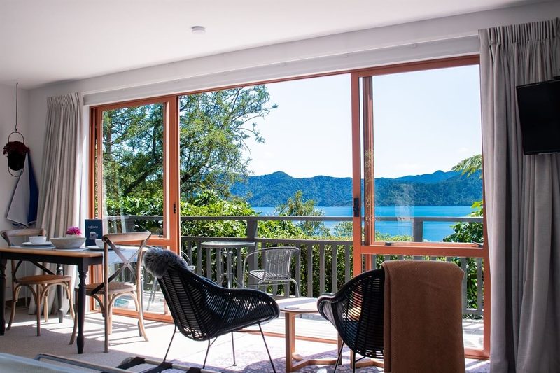 Seaclusion Cottage lounge and dining area facing its deck and Queen Charlotte Sound.