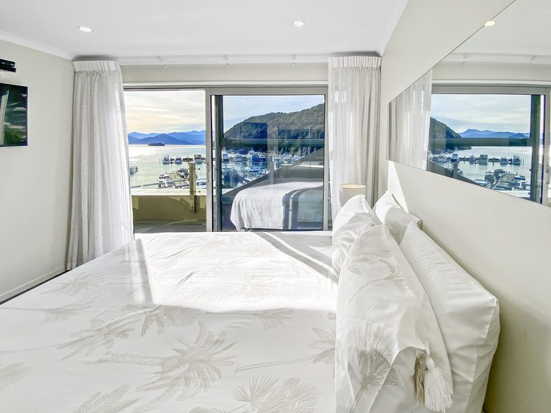Bright double bedroom opening to a balcony with Picton Marina and harbour views.