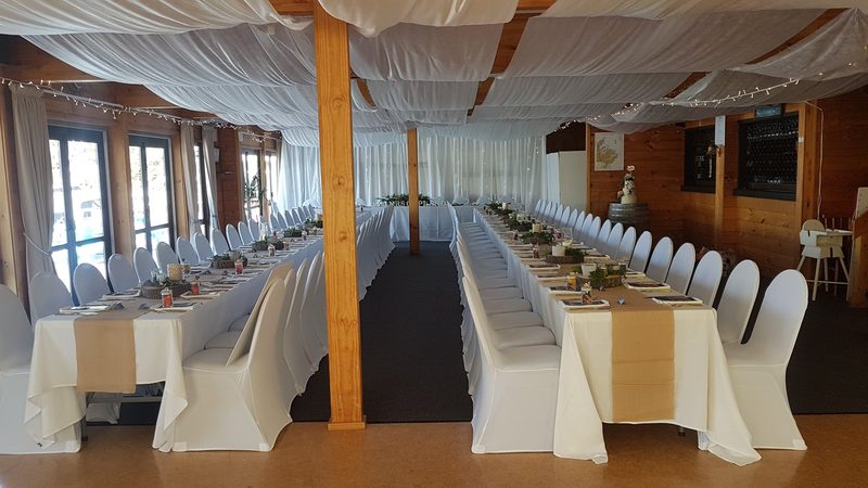 The Wardroom dining room set with long white-clothed tables and chairs beside marina-facing windows.