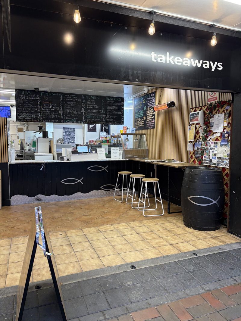 Paperfish order counter, open kitchen and short customer ledge with stools under takeaway signage.